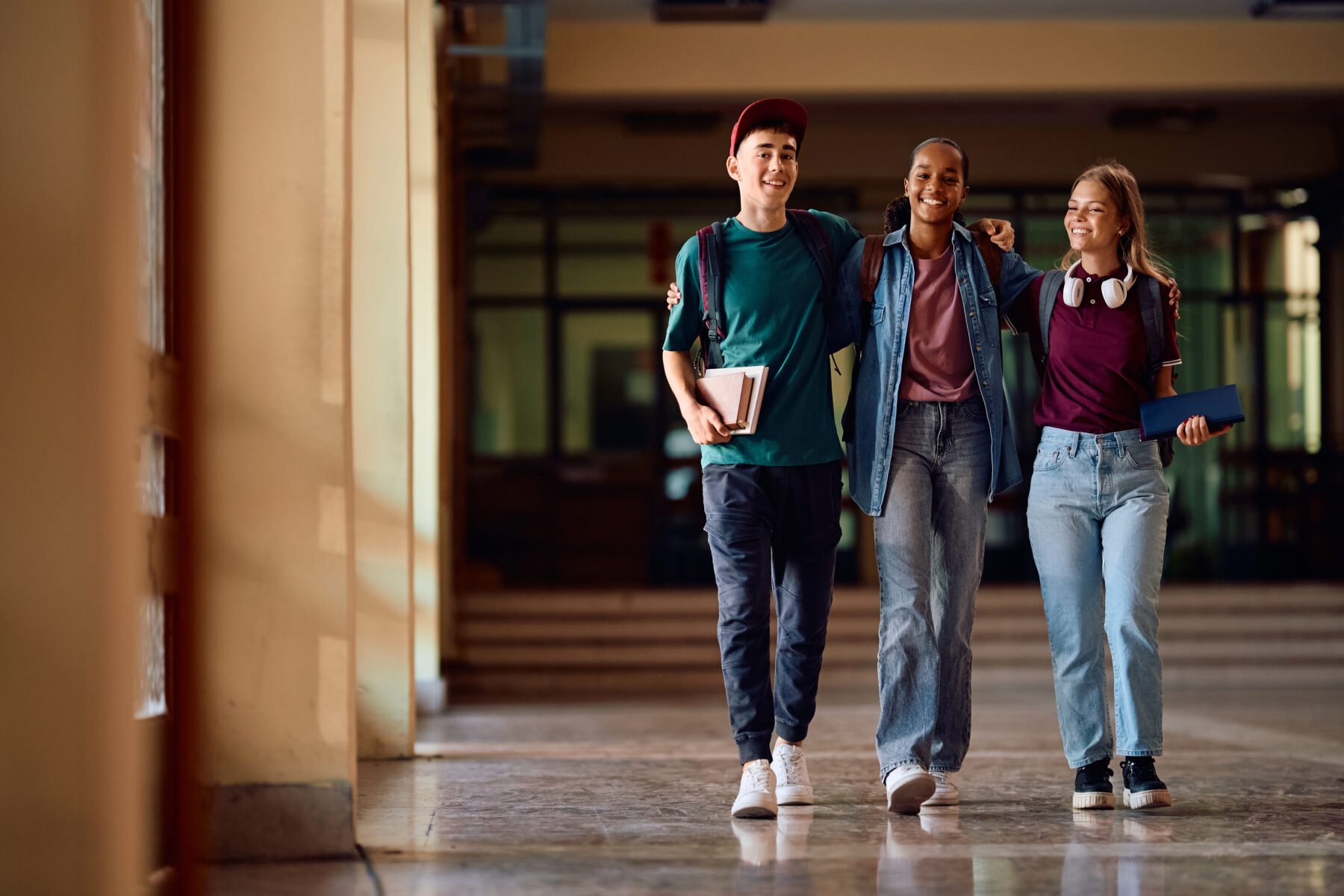 A group of three students walking along a college corridor