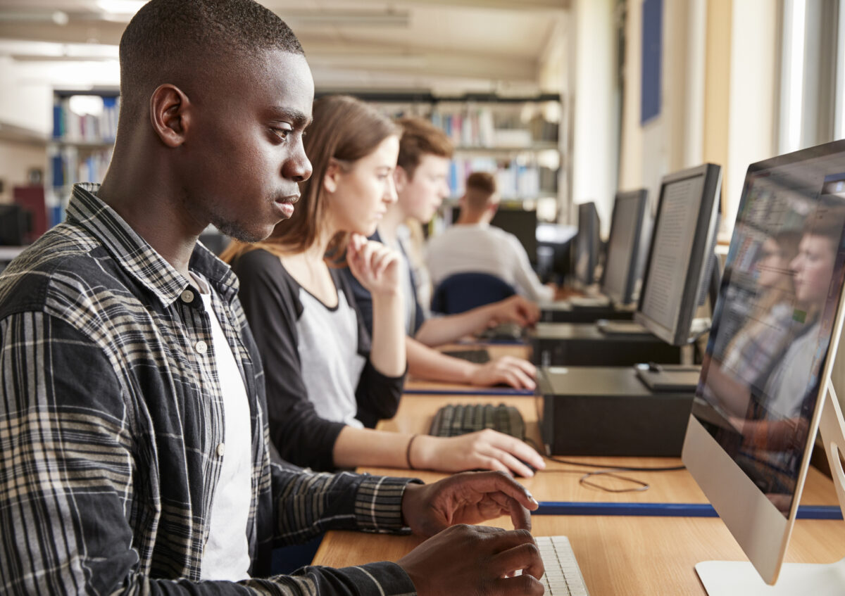 A student at a workstation with others in the background